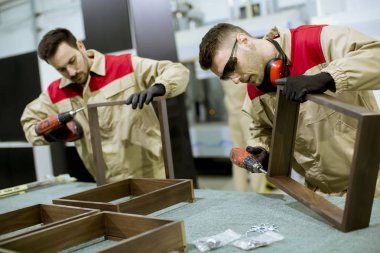 Fabrikada mobilya montajı iki yakışıklı genç işçi
