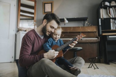 Babam kıza odada nasıl gitar çalacaklarını gösterir.