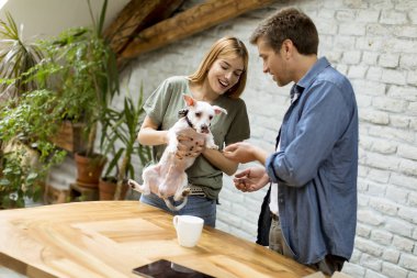 Sevgi dolu çift odada sevimli beyaz köpek ile oynuyor