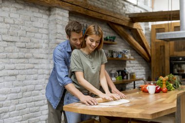 Genç bir çift, kırsal mutfakta pizza pişiriyor.