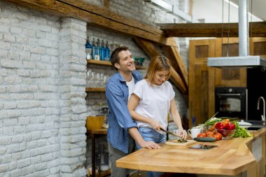 Güzel neşeli genç çift birlikte akşam yemeği pişirme ve rustik mutfakta eğlenmek