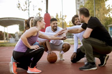 Çok ırklı genç basketbolcular birlikte sahada dinlenen