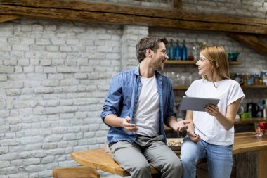 Güzel çift bir dijital tablet kullanıyor ve evde masada otururken gülümseyen