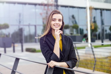 Şirket binası önünde açık havada duran genç iş kadınının portresi