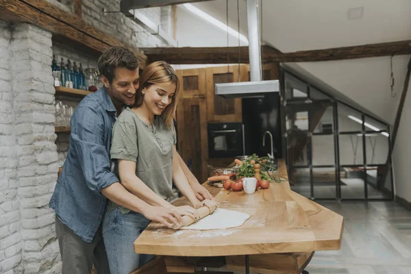 Güzel neşeli genç çift birlikte akşam yemeği pişirme ve rustik mutfakta eğlenmek
