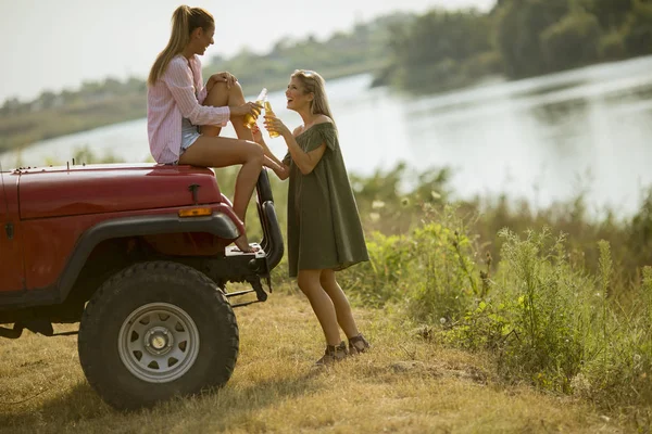 Две Молодые Женщины Веселятся Капоте Красной Машины Реки — стоковое фото