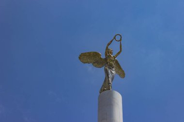 Kuzey Makedonya'nın Üsküp kentinde, Makedonya'nın Düşmüş Kahramanları anıtının tepesinde çelenk tutan altın kanatlı tanrıça kadın