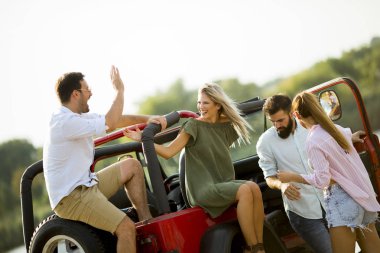 Güneşli sıcak bir yaz gününde açık havada araba ile eğlenen gençlerin grubu