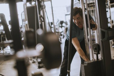 Yakışıklı genç atlet ağırlık plakaları ekleyerek, spor salonunda yaptığı halter egzersiz için hazırlanıyor