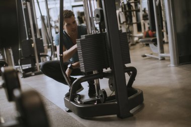 Yakışıklı genç atlet ağırlık plakaları ekleyerek, spor salonunda yaptığı halter egzersiz için hazırlanıyor