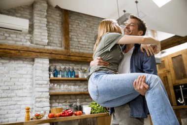 Mutlu genç çift modern mutfakta birbirlerinin tadını çıkarırken, erkek elinde kadın tutarken