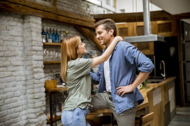 Sevimli genç çift kendi daire mutfağında yemek yaparken sarılma