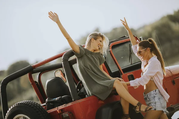 Две Молодые Женщины Веселятся Капоте Машины Озера Жаркий Летний День — стоковое фото