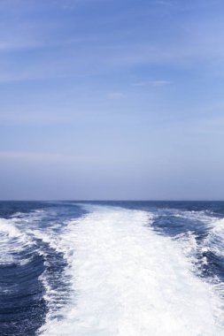 Güzel mavi gökyüzü ile okyanusta sürat teknesi arkasında su sıçraması