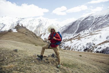 Gürcistan'ın Mtskheta-Mtianeti bölgesinde yüksek enlem dağlarında geleneksel papakha kürk şapkalı genç yürüyüşçü görünümü