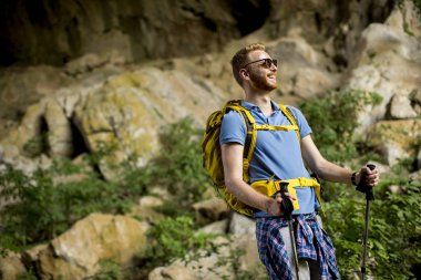 Güneşli bir günde sırt çantası ile yakışıklı genç beyaz erkek yürüyüşçü