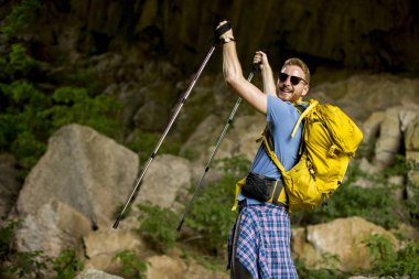 Güneşli bir günde sırt çantası ile yakışıklı genç beyaz erkek yürüyüşçü