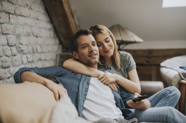 Gülümseyen güzel genç çift rahatlatıcı ve evde Tv izlerken
