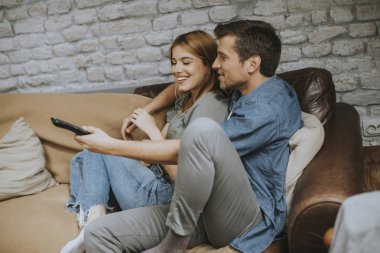 Gülümseyen güzel genç çift rahatlatıcı ve evde Tv izlerken