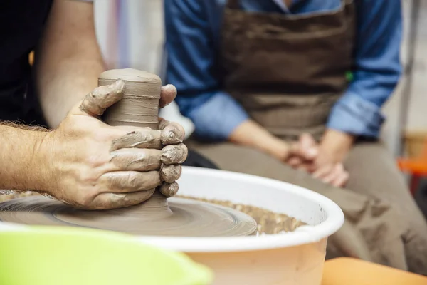 在陶瓷课上 在一位老师的帮助下 一位老妇人在轮子上旋转粘土 — 图库照片