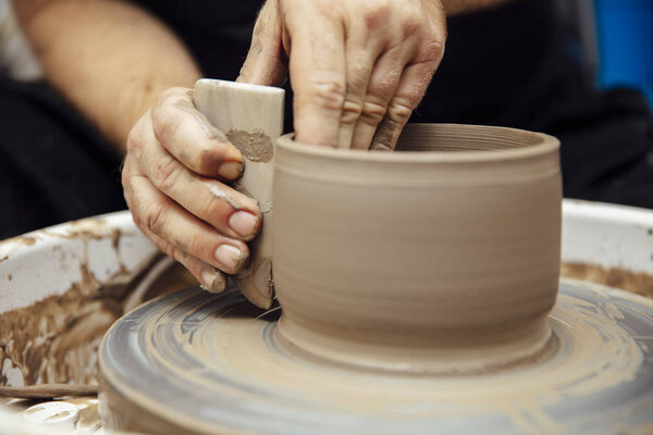 Close up detail view at an mail artist makes clay pottery on a spin wheel