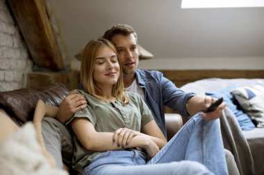 Gülümseyen güzel genç çift rahatlatıcı ve evde Tv izlerken