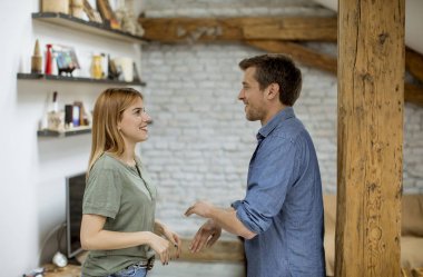 Yakışıklı sevgi dolu genç erkek arkadaşı bir çatı dairede kız arkadaşı el ele tutuşurken gülümseyen