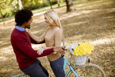 Güz parkında bisikleti olan çok ırklı genç bir çift.