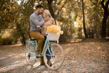 Aktif genç çift Golden Autumn Park 'ta bisiklet sürerken eğleniyor.