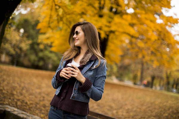 在秋天的公园喝咖啡的年轻女子 — 图库照片