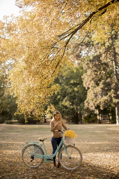 Ładna Młoda Kobieta Rowerem Pomocą Smartfona Jesiennym Parku — Zdjęcie stockowe