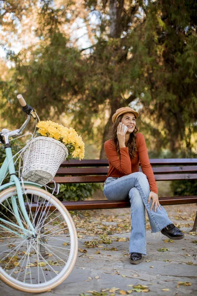 Mulher Bonita Usando Telefone Parque Outono Sentado Banco Pela Bicicleta — Fotografia de Stock
