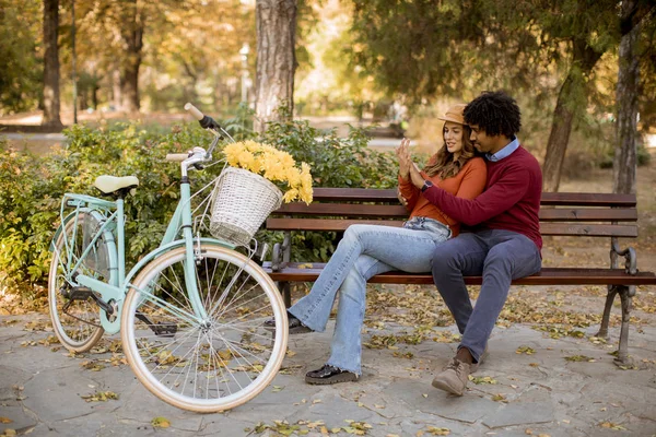 在秋天的城市公园里 一对多情的年轻夫妇坐在长椅上 — 图库照片