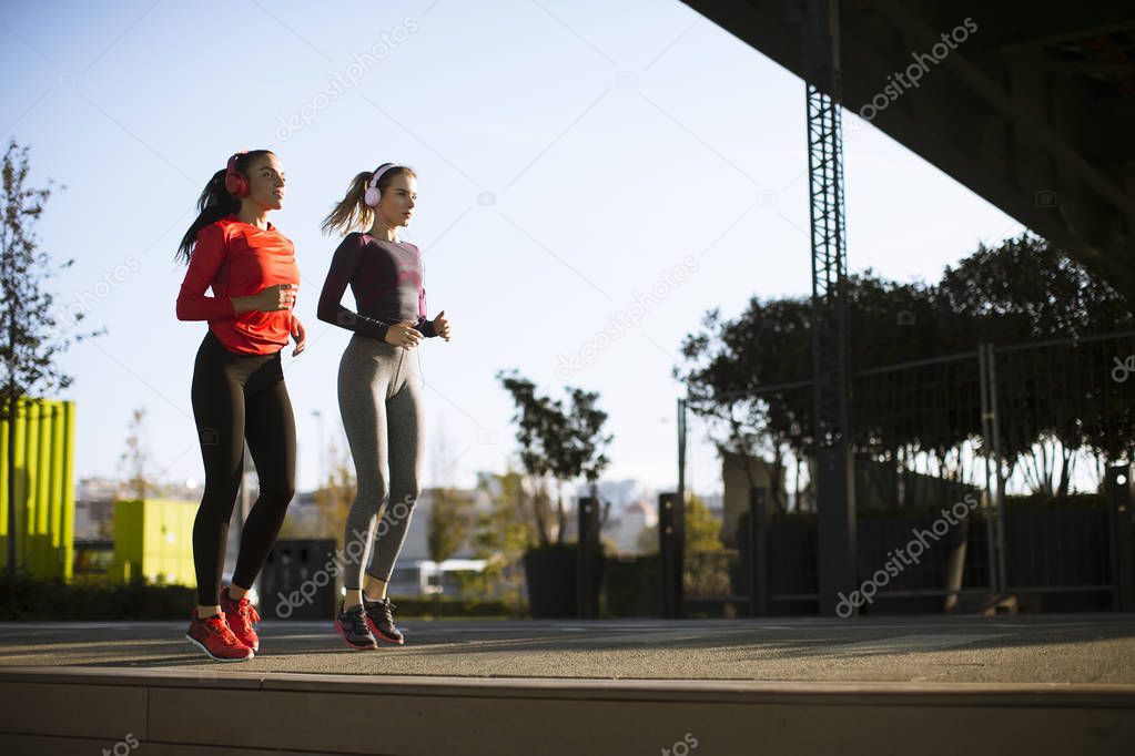 Scenery of two female joggers pursuing their activity in urban outdoors