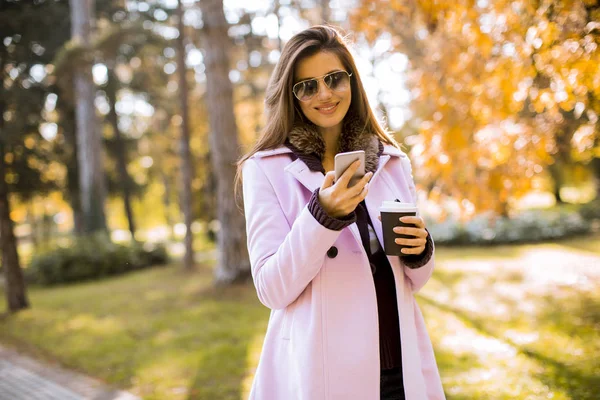 Jovencita Alegre Vistiendo Abrigo Rosa Usando Teléfono Soleado Parque Tomando —  Fotos de Stock