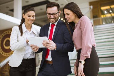 İş arkadaşı görevdeyken dijital tablet kullanan üç genç iş adamının portresi