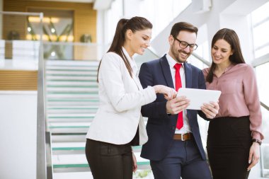 İş arkadaşı görevdeyken dijital tablet kullanan üç genç iş adamının portresi