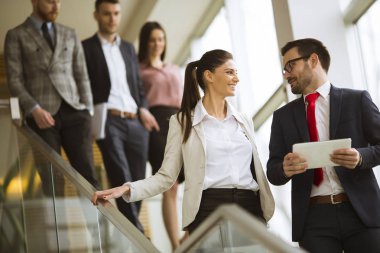 Genç iş ortakları modern ofiste merdivenlerden inerken iş sonuçlarını analiz ederler.