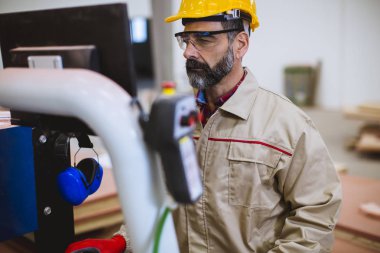 Modern ahşap fabrikada kontrol panelinde duran yaşlı adam işletim makinelerinin portresi.