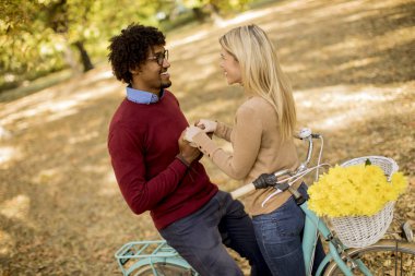 Güz parkında bisikleti olan çok ırklı genç bir çift.