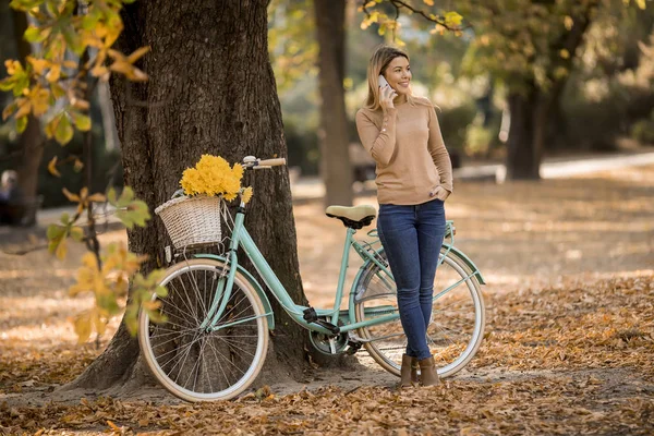 Bella Giovane Donna Con Bicicletta Utilizzando Smartphone Nel Parco Autunnale — Foto Stock