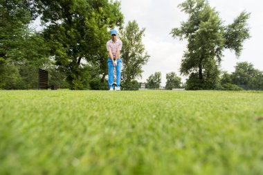 Genç adam golf sahasında oynuyor.