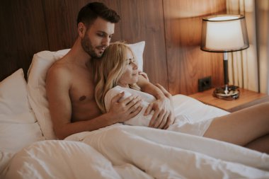 Evlerinde yataklarında kucaklaşan sevimli genç bir çift.