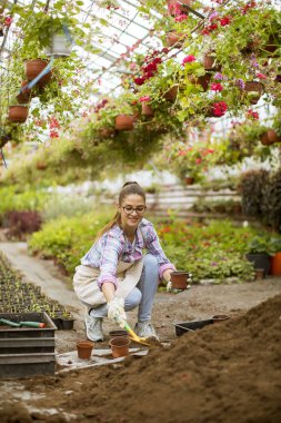 Çiçek bahçesinde çalışan güzel genç bayana bakın.