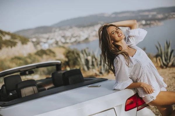 阳光明媚的夏日 坐在海边的白色出租车旁的漂亮女子 — 图库照片
