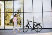 junge Frau mit E-Bike auf Handy im Freien
