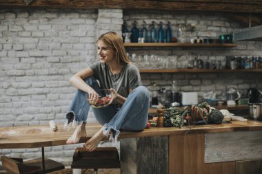 Genç bir kadın kırsal mutfakta vejetaryen yemeği yiyor ve detoks yapıyor.
