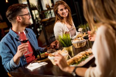 Bir grup mutlu genç restoranda yemek yiyor.