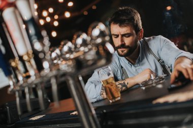Gece kulübünde bira içip sigara içen genç bir adam.
