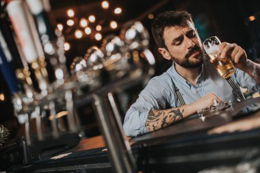 Gece kulübünde bira içip sigara içen genç bir adam.